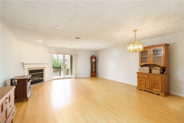 51 Scenic Dr, West Warwick, RI 02893 - unfurnished living room featuring baseboards, a chandelier, a glass covered fireplace, and light wood-type flooring