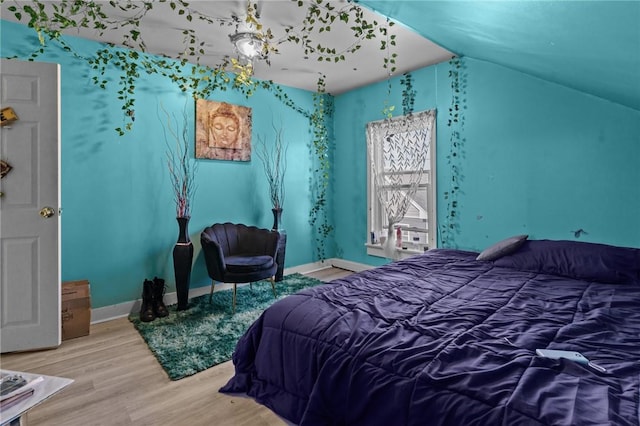 bedroom with baseboards, wood finished floors, and vaulted ceiling