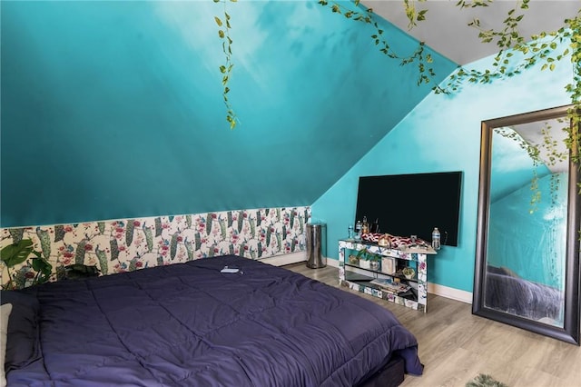 bedroom with baseboards, wood finished floors, and lofted ceiling