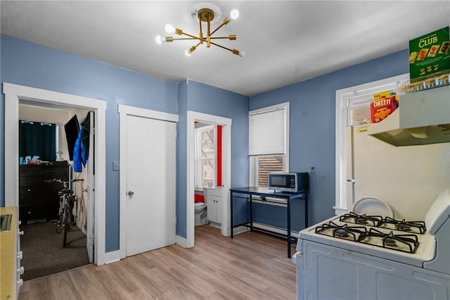 kitchen featuring light wood-type flooring, baseboards, stainless steel microwave, a chandelier, and white range with gas stovetop