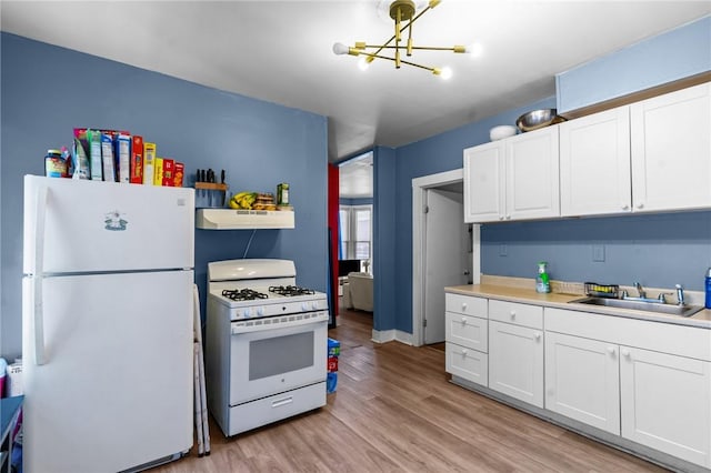 kitchen with white appliances, white cabinetry, under cabinet range hood, and a chandelier
