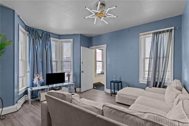 living area with baseboards, a chandelier, a healthy amount of sunlight, and wood finished floors