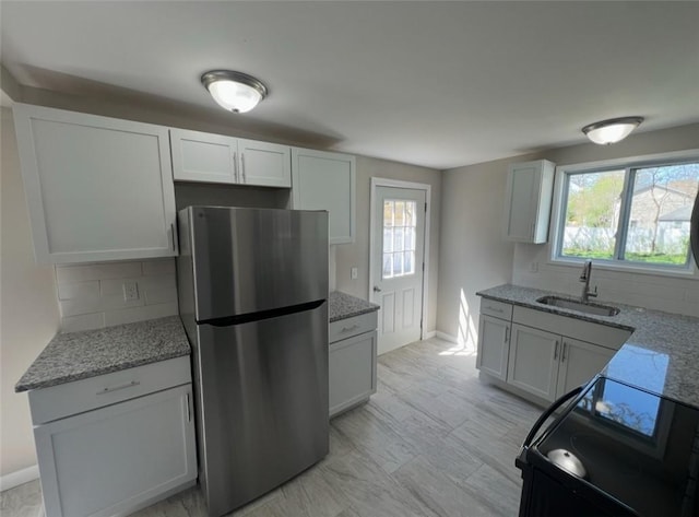 191 Canfield Ave, Warwick, RI 02889 - kitchen featuring freestanding refrigerator, a sink, decorative backsplash, and light stone countertops