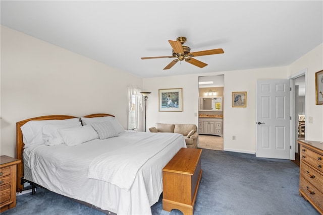 bedroom with baseboards, a ceiling fan, dark carpet, and ensuite bath