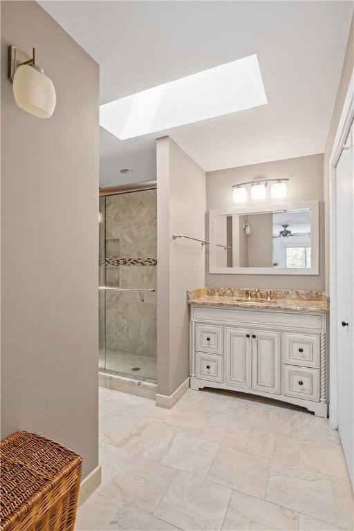 bathroom featuring a skylight, a stall shower, baseboards, vanity, and marble finish floor