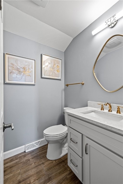 bathroom with visible vents, vanity, lofted ceiling, wood finished floors, and toilet