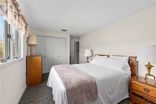 bedroom with baseboards, a closet, dark colored carpet, and visible vents