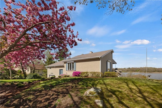 view of property exterior featuring a lawn and a water view