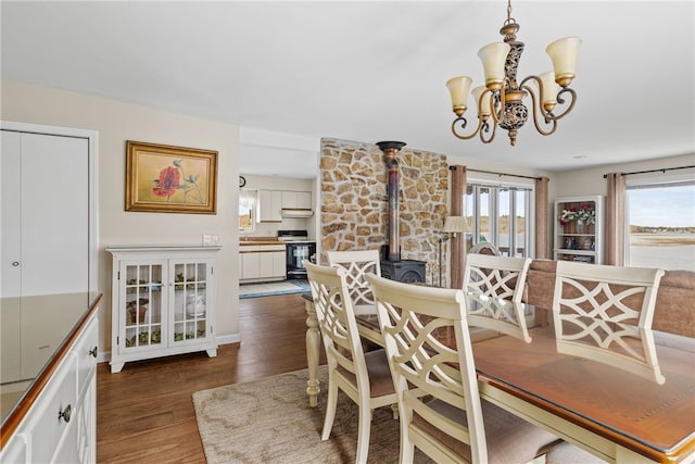 dining space with a wood stove, wood finished floors, and a chandelier