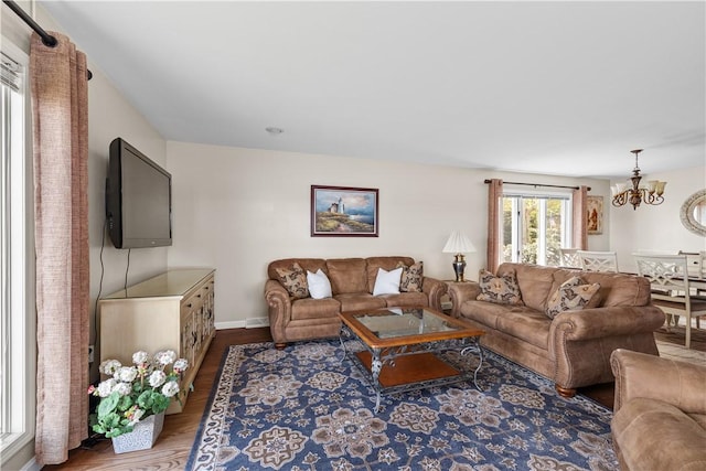 living room featuring baseboards, wood finished floors, and a notable chandelier
