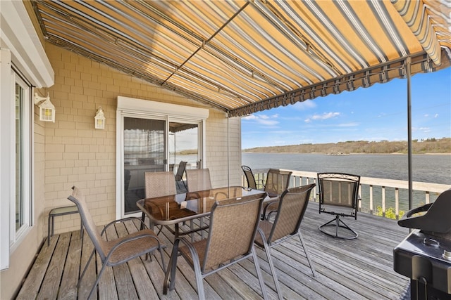 wooden terrace with grilling area, a water view, and outdoor dining area