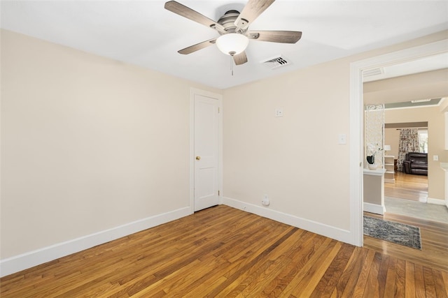spare room with ceiling fan, visible vents, baseboards, and light wood finished floors