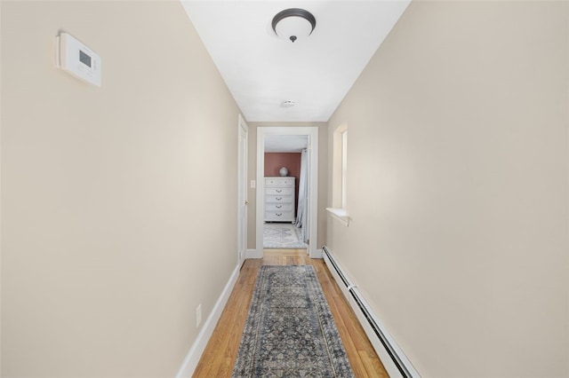 hall with baseboards, a baseboard heating unit, and light wood-style flooring