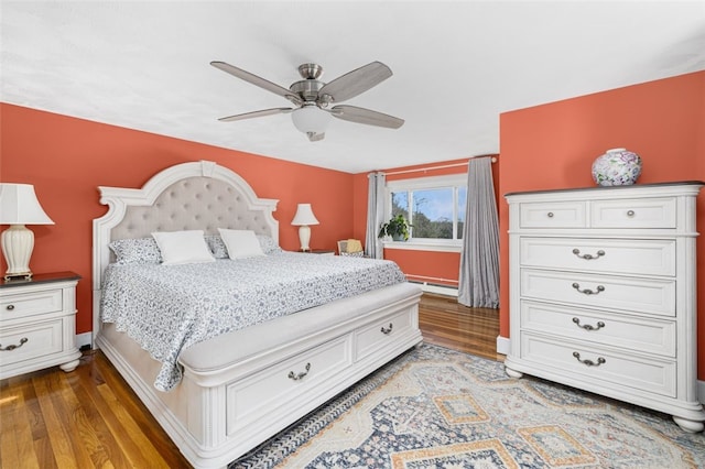 bedroom with baseboard heating, a ceiling fan, baseboards, and light wood-style flooring