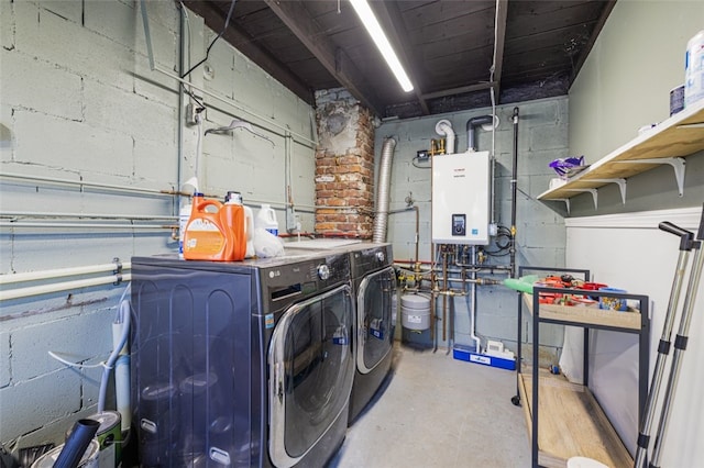 washroom with water heater, concrete block wall, laundry area, and independent washer and dryer