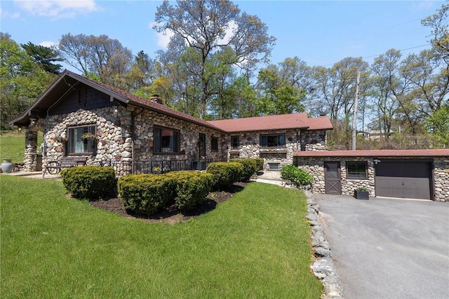 view of front facade featuring an attached garage, a front lawn, stone siding, and aphalt driveway