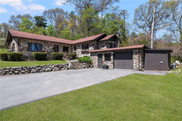view of front facade featuring an attached garage, driveway, a front lawn, and stone siding
