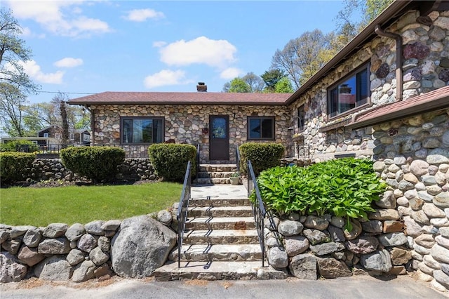 view of front of home with stone siding and a front lawn