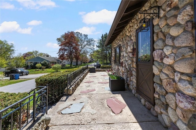 view of side of home with fence and stone siding