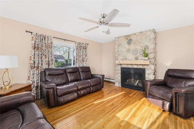 living area featuring wood finished floors, a ceiling fan, a baseboard heating unit, and a fireplace