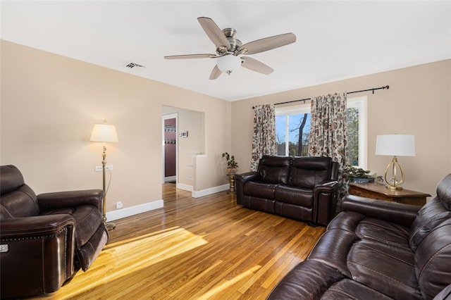 living area with baseboards, a ceiling fan, wood finished floors, and visible vents