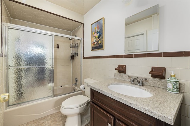 full bath featuring tile patterned flooring, vanity, toilet, enclosed tub / shower combo, and tile walls