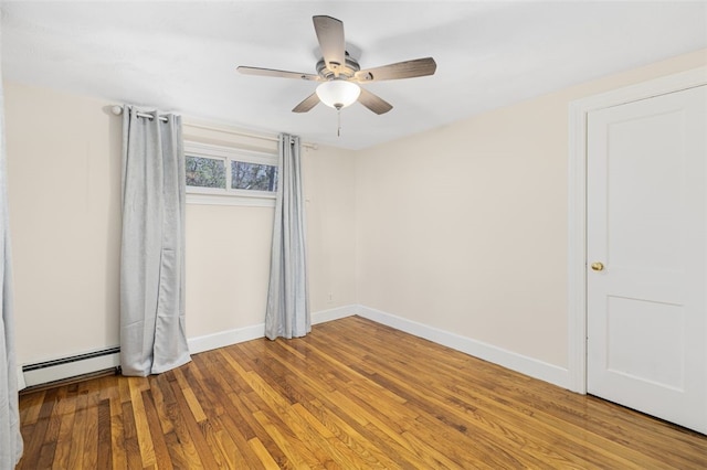 spare room with baseboards, ceiling fan, wood finished floors, and a baseboard radiator