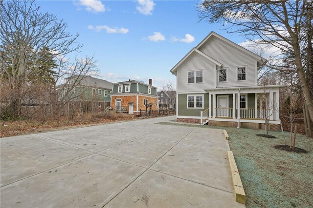 rear view of house featuring a porch and concrete driveway