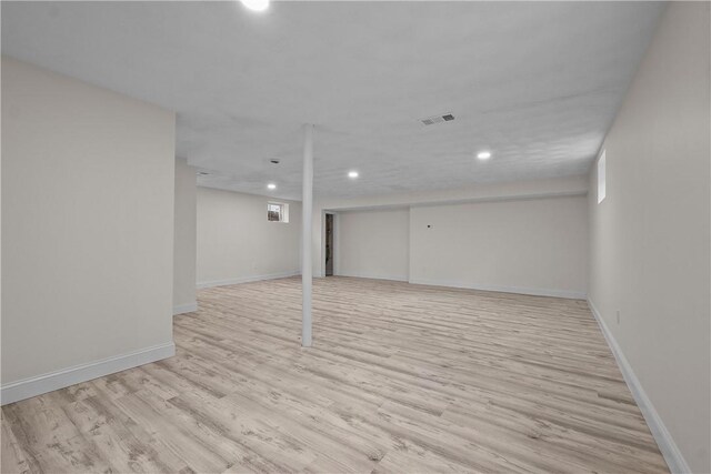 finished below grade area with baseboards, light wood finished floors, recessed lighting, and visible vents