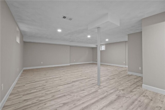 finished basement featuring recessed lighting, baseboards, visible vents, and light wood-style floors