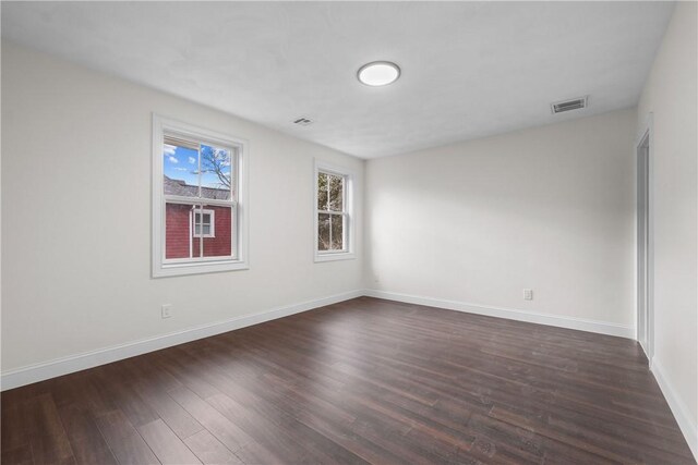 empty room with baseboards, dark wood-style floors, and visible vents