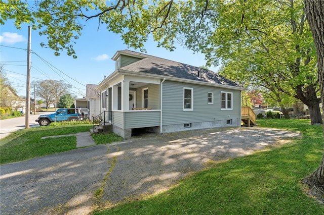 exterior space with covered porch, a lawn, and roof with shingles