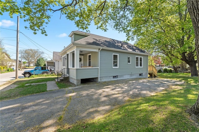 exterior space with roof with shingles, a yard, and a porch