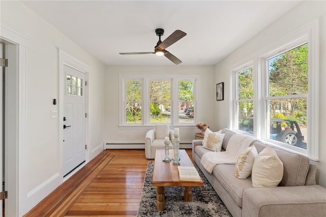 living area featuring ceiling fan, baseboards, a baseboard radiator, and wood finished floors