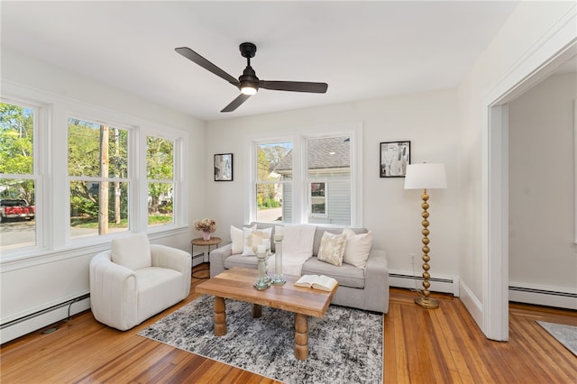 living area featuring light wood-style floors, baseboard heating, and a ceiling fan