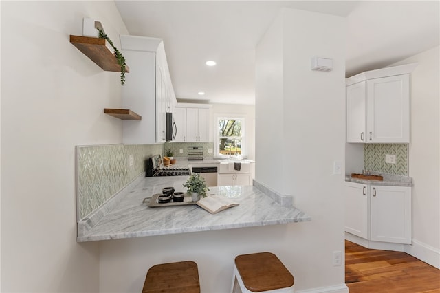 kitchen featuring appliances with stainless steel finishes, tasteful backsplash, open shelves, and a kitchen bar