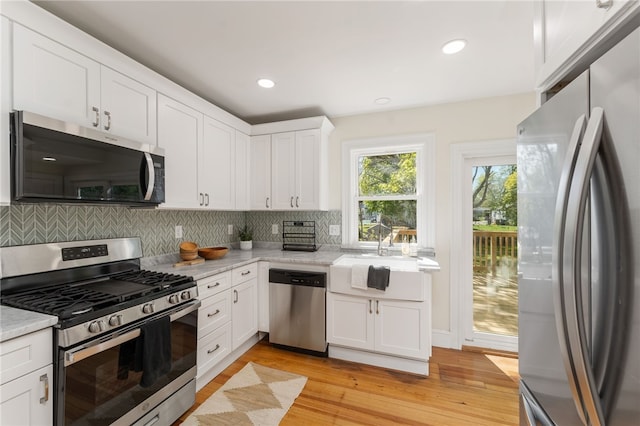 kitchen featuring light countertops, backsplash, appliances with stainless steel finishes, and a sink