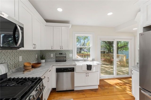 kitchen featuring a sink, decorative backsplash, white cabinetry, and stainless steel appliances