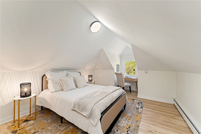 bedroom featuring vaulted ceiling, baseboards, a baseboard heating unit, and wood finished floors