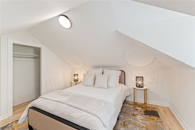 bedroom featuring a closet, baseboards, wood finished floors, and vaulted ceiling