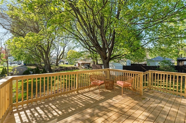 wooden deck with an outdoor structure, a shed, and fence