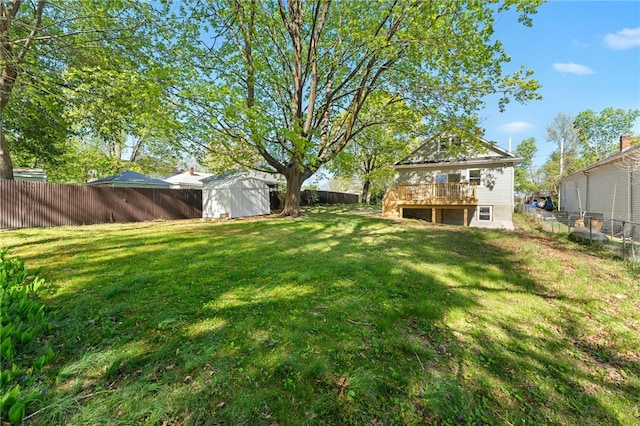 view of yard with a fenced backyard, a shed, an outbuilding, and a deck