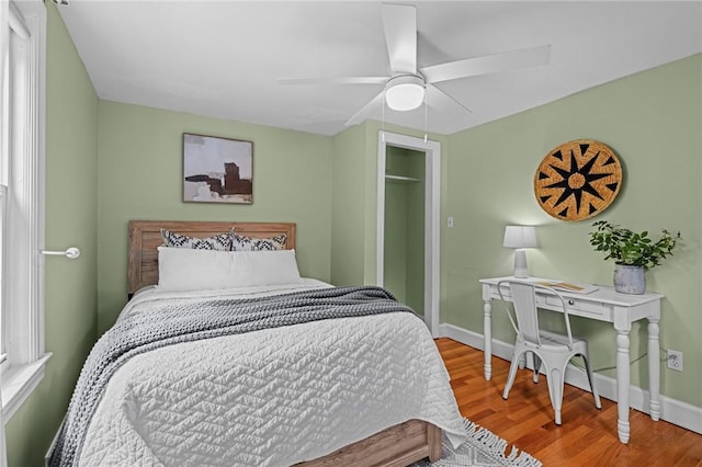 bedroom featuring baseboards, ceiling fan, wood finished floors, and a closet