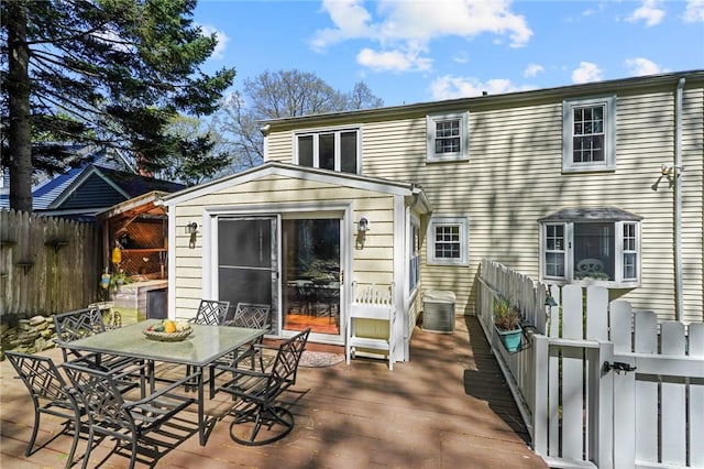 rear view of house with a deck, fence, and outdoor dining space