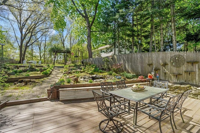 deck with a fenced backyard, a vegetable garden, and outdoor dining space