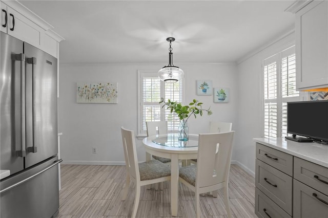 dining room with crown molding, baseboards, a healthy amount of sunlight, and light wood finished floors