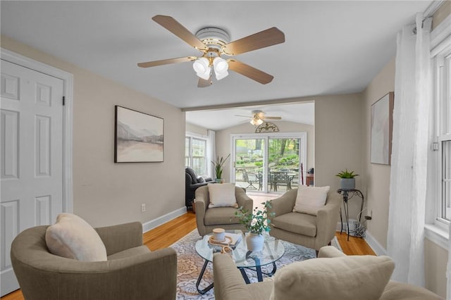 living room featuring a ceiling fan, baseboards, light wood-style flooring, and lofted ceiling