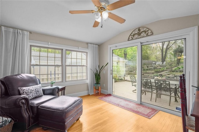 living area featuring wood finished floors, a ceiling fan, baseboards, and lofted ceiling