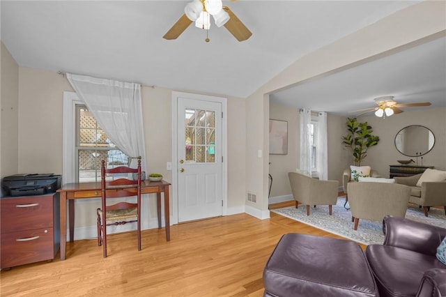 living area with visible vents, lofted ceiling, baseboards, a ceiling fan, and light wood finished floors