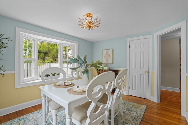 dining space with baseboards, a notable chandelier, and wood finished floors